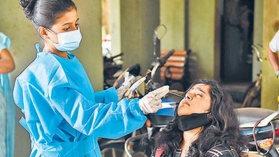 A health worker collects swab sample of a resident for a Covid-19 test in Mumbai. Maharashtra recorded under 1,000 daily cases after a week as 809 infections were reported on Monday, the lowest single-day caseload since May 2, 2020. (PTI/File)