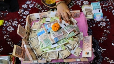 A person worships currency notes as part of a ritual during Dhanteras, in Ahmedabad. (PTI) A person worships currency notes as part of a ritual during Dhanteras, in Ahmedabad. (PTI)