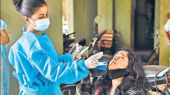 A health worker collects swab sample of a resident for a Covid-19 test in Mumbai. Maharashtra recorded under 1,000 daily cases after a week as 809 infections were reported on Monday, the lowest single-day caseload since May 2, 2020. (PTI/File)