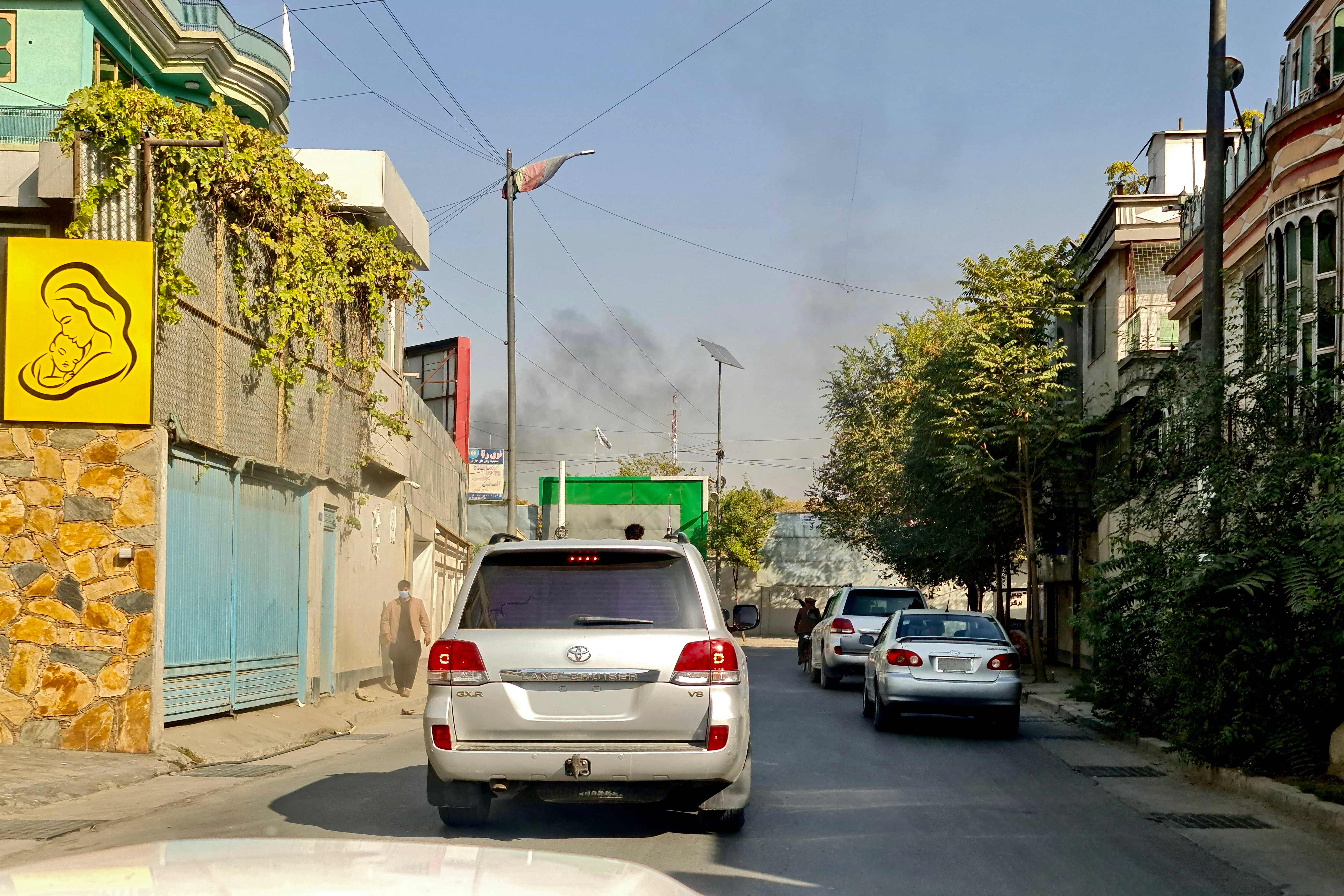 Vehicles move along a road against the backdrop of smoke rising from the site of blast in Kabul. (Photo by AFP)