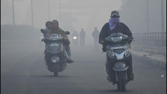 Commuters ply on their two-wheelers on a hazy morning witnessed on the next day of Diwali, in Ludhiana on Friday. (Harsimar Pal Singh/Hindustan Times)