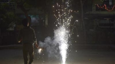 A man burns firecrackers on Diwali at Sector 19 in Noida on Friday. (Sunil Ghosh)