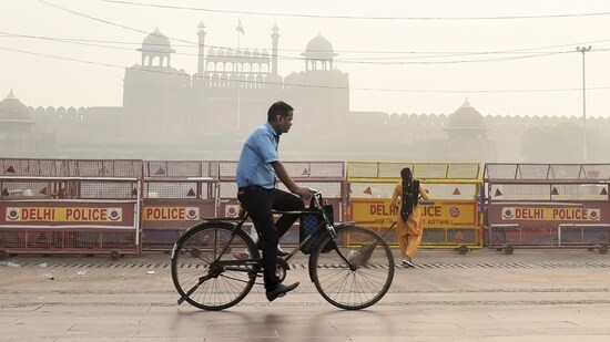 A man rides a bicycle in front of the historic Red Fort, shrouded in smog post-Diwali celebrations in New Delhi.&nbsp;(File Photo / PTI)