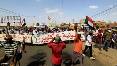 Protesters carry a banner and national flags as they march against the Sudanese military's recent seizure of power and ousting of the civilian government, in the streets of the capital Khartoum, Sudan.&nbsp; (REUTERS)