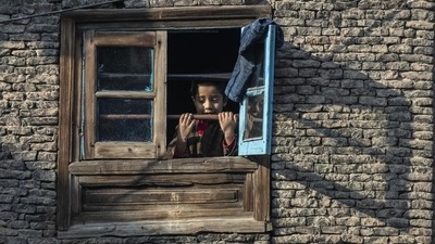 A child looks out of a window in the old part of Srinagar on Sunday. Jammu and Kashmir Police have formed a team to probe constable Tawseef Ahmad Wani’s killing. (AP)