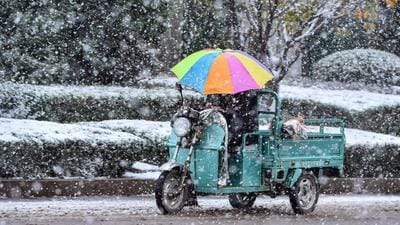 A person riding a tricycle with an umbrella during snowfall in China’s eastern Shandong province. More than 200,000 residents of Haiyang city in the eastern coastal province of Shandong, China have begun to receive nuclear power-generated central heating for winter. (AFP)