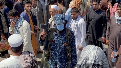 A member of Taliban security forces stands guard among crowds of people walking past in a street in Kabul, Afghanistan&nbsp; (Reuters Photo)