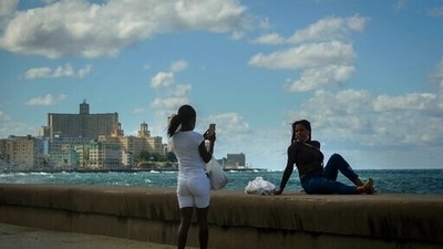 A woman takes a photo of another on the Malecon in Havana, Cuba, Monday, Nov. 8, 2021. Cuba is preparing to reopen to the world on Nov. 15, following lockdown restrictions. (AP Photo / Ramon Espinosa) A woman takes a photo of another on the Malecon in Havana, Cuba, Monday, Nov. 8, 2021. Cuba is preparing to reopen to the world on Nov. 15, following lockdown restrictions. (AP Photo / Ramon Espinosa)