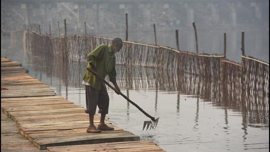 An MCD worker cleans the premises of a Chhath ghat made on the bank of Bhalswa Lake on Tuesday. (Sanchit Khanna/HT)