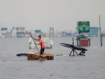 A man uses a fridge as raft along a flooded section of Marina beach in Chennai.(AFP) A man uses a fridge as raft along a flooded section of Marina beach in Chennai.(AFP)