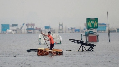 A man uses a fridge as raft along a flooded section of Marina beach in Chennai. (AFP) A man uses a fridge as raft along a flooded section of Marina beach in Chennai. (AFP)