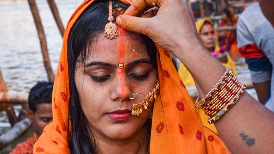 A woman applies vermillion on another woman as they pray to the sun god near the Ganga river during the Chhath Puja festival in Patna. Today Sandhya Arghya was offered to Sun God by fasting women.(PTI)