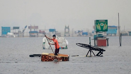 A man uses a fridge as raft along a flooded section of Marina beach in Chennai.(AFP)