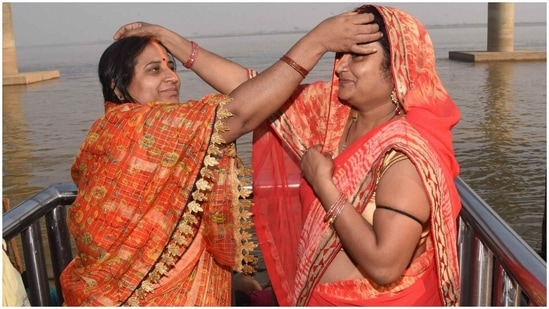 Two devotees put vermillion on each other’s forehead after their bath in Ganges.(PTI)