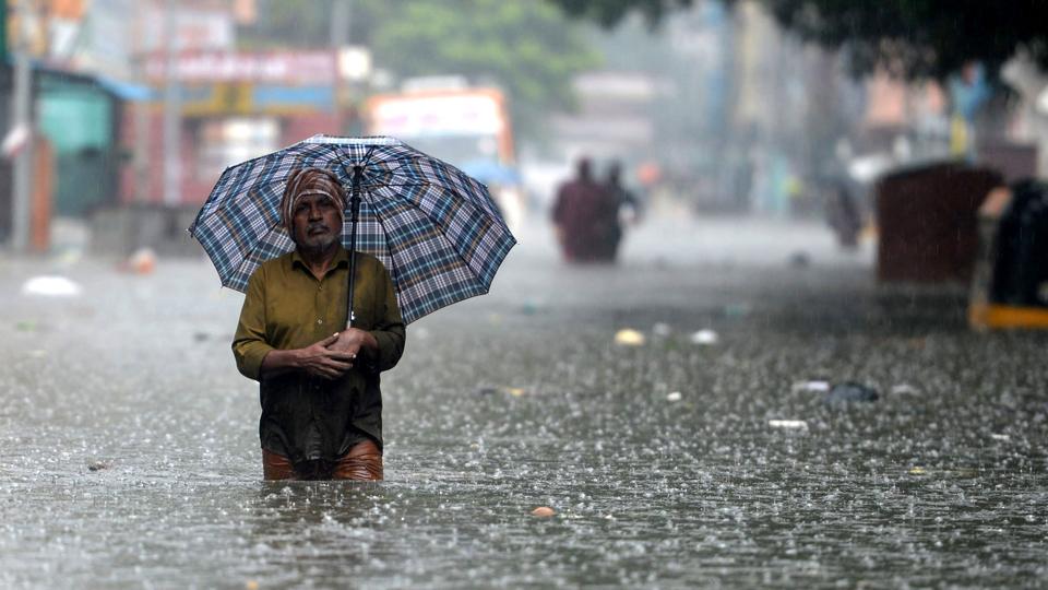 A man holds an umbrella as he wades through a flooded street after heavy monsoon rain in Chennai. (AFP Photo)