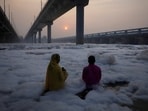 A couple worships the Sun god as they stand amidst the toxic foam of Yamuna river in Delhi.(REUTERS)