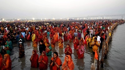 After taking a dip in the Ganga river, women in red sarees fold their hands and offer prayers to the Sun God. (PTI) After taking a dip in the Ganga river, women in red sarees fold their hands and offer prayers to the Sun God. (PTI)