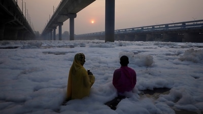 A couple worships the Sun god as they stand amidst the toxic foam of Yamuna river in Delhi. (REUTERS)