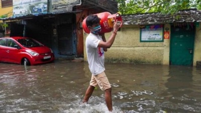 A man carries a cooking gas cylinder and wades past a waterlogged street in Chennai. (AP) A man carries a cooking gas cylinder and wades past a waterlogged street in Chennai. (AP)