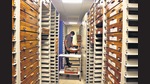 Mounted specimens in wooden caskets are stacked on movable shelves in a temperature-controlled room. Mounted specimens in wooden caskets are stacked on movable shelves in a temperature-controlled room.