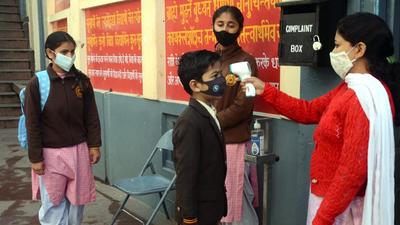 An employee checking the body temperature of a student at Arya Samaj School, Shimla. The state government had decided to open schools last week. (Deepak Sansta/HT)