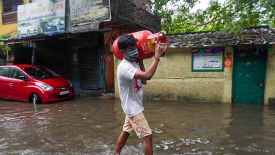 Un hombre lleva una bombona de gas para cocinar y pasa junto a una calle inundada en Chennai, en el estado de Tamil Nadu, en el sur de India, & nbsp; (Foto de archivo / AP)
