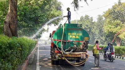 Workers spray water as part of efforts to curb air pollution in New Delhi on Sunday. (PTI) Workers spray water as part of efforts to curb air pollution in New Delhi on Sunday. (PTI)