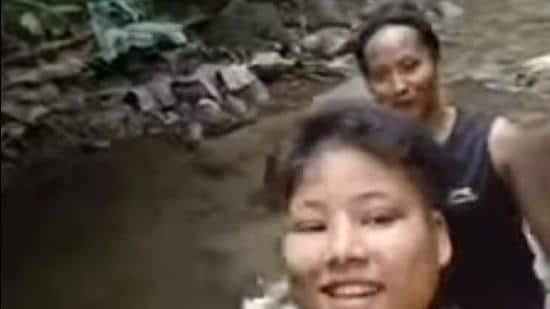 A screen grab of a video showing Nayanmani Chetia and Sabita Chetia (in front) crossing a stream inside a forest. (SOURCED.)