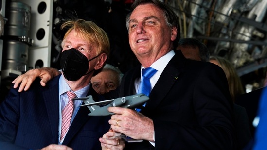 Brazilian President Jair Bolsonaro embraces an official inside of a Brazilian Air Force Embraer KC-390 at the Dubai Air Show.(AP)