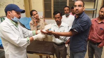 The cash transfer shop owner getting first-aid after the attack; his wife suffered bullet injury on her thigh while the toddler daughter was injured by splinters of the bullet. Ludhiana police are examining closed-circuit television cameras in the area for leads. (HT Photo)