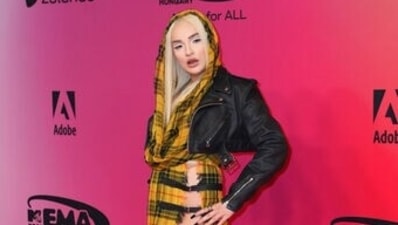 Kim Petras poses for the photographers upon arrival at the European MTV Awards in yellow and black checkered ensemble with waist-high side slit. (AP)