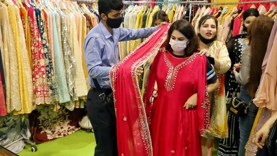 A woman tries a red salwar suit at a stall selling Indian attires at the 40th India International Trade Fair at Pragati Maidan in New Delhi.(ANI)