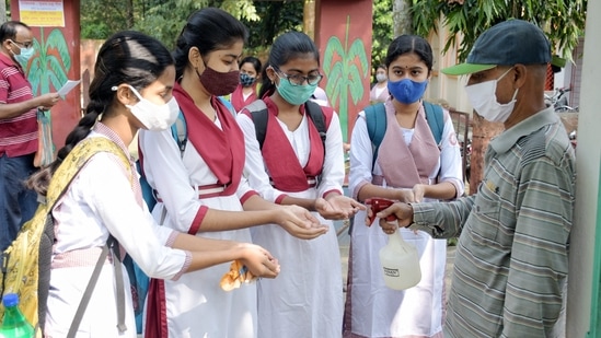 Students sanitize their hands before entering their school premise in Nadia, West Bengal.(PTI)