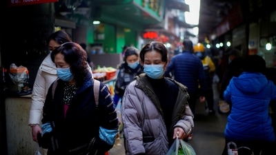 People wearing face masks walk on a street market in the early months of the outbreak of the coronavirus disease (COVID-19) in Wuhan, Hubei province, China. (REUTERS)