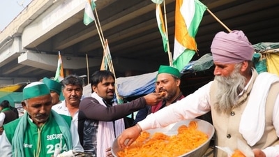Farmers who have been protesting at the Ghazipur protest site near Delhi-UP border feed each other sweets and celebrate after PM Modi announced that he will repeal the controversial farm laws. (REUTERS)