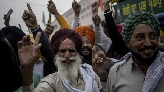 Farmers celebrate at a protest site on the Delhi-Haryana border crossing in Singhu, in New Delhi on Friday. Prime Minister Narendra Modi announced that the Centre would scrape the three farm laws ahead of crucial state elections. (Bloomberg)