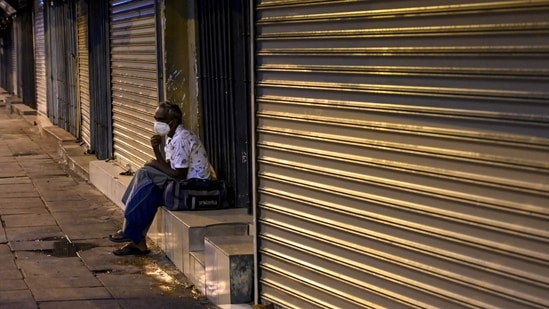 A man sits in front of closed shops on a deserted street in Colombo (AFP)