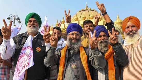 Farmers pose for a picture and shout slogans to celebrate the Centre’s decision to repeal three agricultural reform laws that sparked almost a year of huge protests across the country.(AFP)
