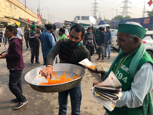 A man distributes sweets to celebrate news of the repeal of farm laws they were protesting against, in Ghazipur (AP Photo) A man distributes sweets to celebrate news of the repeal of farm laws they were protesting against, in Ghazipur (AP Photo)