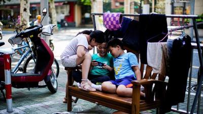 Children look at a phone on a street in Shanghai, China. (REUTERS) Children look at a phone on a street in Shanghai, China. (REUTERS)