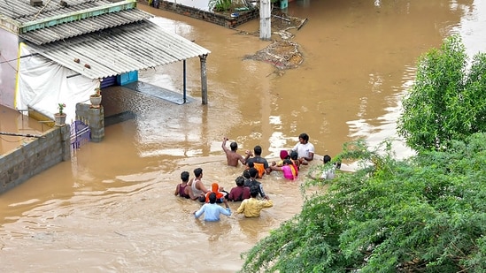 As many as 1,549 houses were completely damaged due to flash floods. In picture - Residents wade through a flood-affected area in Nellore district of Andhra Pradesh.(PTI)