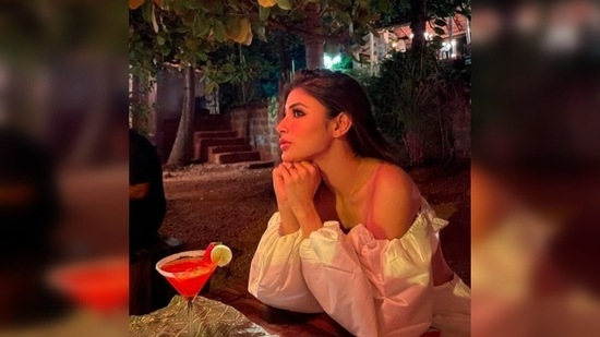 With a drink in front of her, and sitting aloof, Mouni Roy wondered if "the stars gaze back" at humans.(Instagram/@imouniroy)