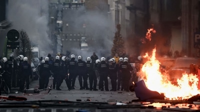Belgian riot police stand by a burning trash can as clashes erupt during a demonstration against Covid-19 measures, including the country's health pass, in Brussels. (AFP) Belgian riot police stand by a burning trash can as clashes erupt during a demonstration against Covid-19 measures, including the country's health pass, in Brussels. (AFP)