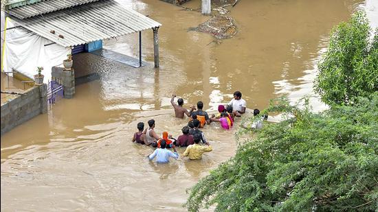 Residents wade through a flood-affected area in Nellore district of Andhra Pradesh on Sunday. (PTI PHOTO.) Residents wade through a flood-affected area in Nellore district of Andhra Pradesh on Sunday. (PTI PHOTO.)