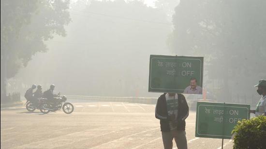 New Delhi, India - Nov. 21, 2021: Civil Defence personnel hold placards urging commuters to switch off their car engines during traffic stoppage at Tilak Marg on a hazy morning in New Delhi, India, on Sunday, November 21, 2021. (Photo by Arvind Yadav/ Hindustan Times)