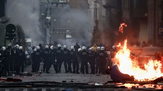 Belgian riot police stand by a burning trash can as clashes erupt during a demonstration against Covid-19 measures, including the country's health pass, in Brussels.(AFP)