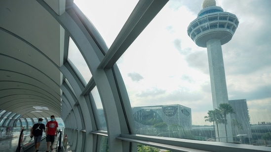 People walk along the link bridge to a terminal at Changi International Airport in Singapore (Photo by Roslan RAHMAN / AFP) People walk along the link bridge to a terminal at Changi International Airport in Singapore (Photo by Roslan RAHMAN / AFP)