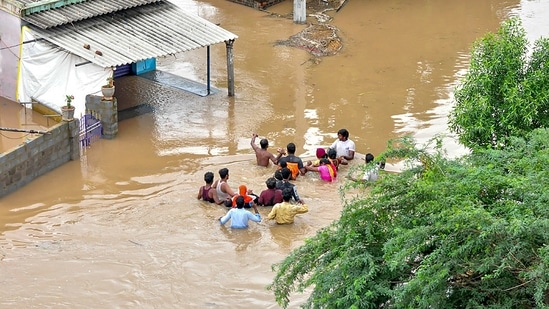 Residents wade through a flood-affected area in Nellore district of Andhra Pradesh.(PTI)