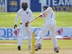 Sri Lankan batter Dhananjaya de Silva hits the wicket while attempting to stop the ball being fallen on it as West Indies' fielder Nkrumah Bonner watches during the day two of first Test match.