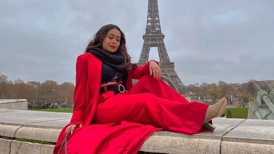 She layered it with a full sleeves red jacket that came with a flowy tail and completed her attire with a black muffler wound around her neck and a pair of beige block heels.(Instagram/nehakakkar)